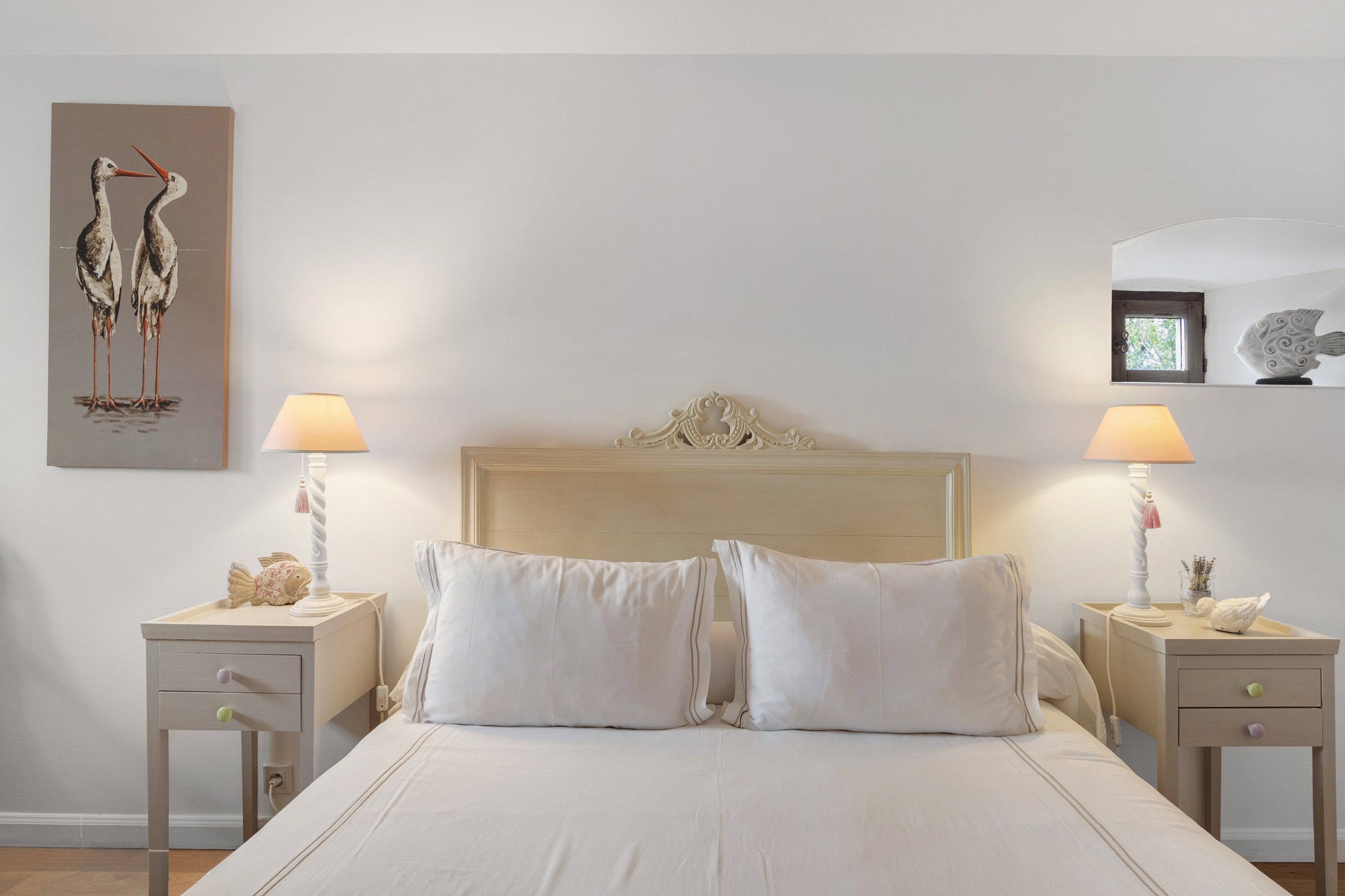 Une chambre avec un grand lit, deux tables de chevet et des œuvres d’art murales.