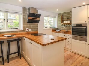 A modern kitchen with a central island, built-in oven, and white cabinetry. - Charming Wrens Nest Retreat (Kingsbridge)