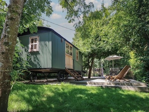 Une maison mobile verte avec un petit porche et une terrasse.