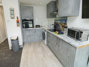 A modern kitchen with grey cabinets, a built-in oven, a microwave, and a sink. - Sunny View, Dawlish Warren (Dawlish)