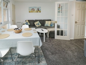 A living room with a dining table, chairs, a sofa, and a painting on the wall. - Sunny View, Dawlish Warren (Dawlish)
