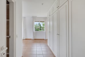 Ein Korridor mit Fenster, weißen Wänden und Fliesenboden.