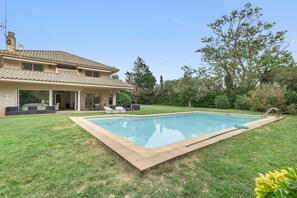 Ein Haus mit Swimmingpool, Terrasse und Gartenmöbeln sowie einem Garten.