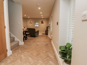 A hallway with a herringbone floor, a staircase, a sofa, a table, and a potted plant. - Henside Cottage, Settle (Settle)
