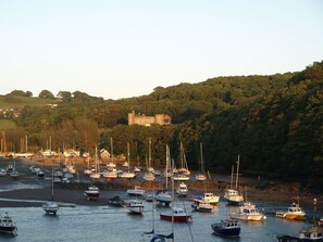 A harbor with numerous boats docked, a castle on a hill, and a forested landscape. - Penn-Curzon Apartment in Devon (Ilfracombe)