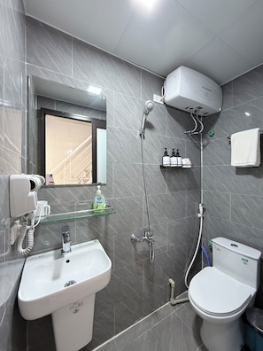Une salle de bain moderne équipée d’une douche, de toilettes, d’un lavabo et d’un sèche-cheveux.