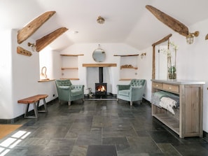 A spacious room with a fireplace, two armchairs, a wooden bench, and a cabinet with a mirror.