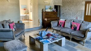 A living room with two sofas, a coffee table with magazines, and a stone wall.
