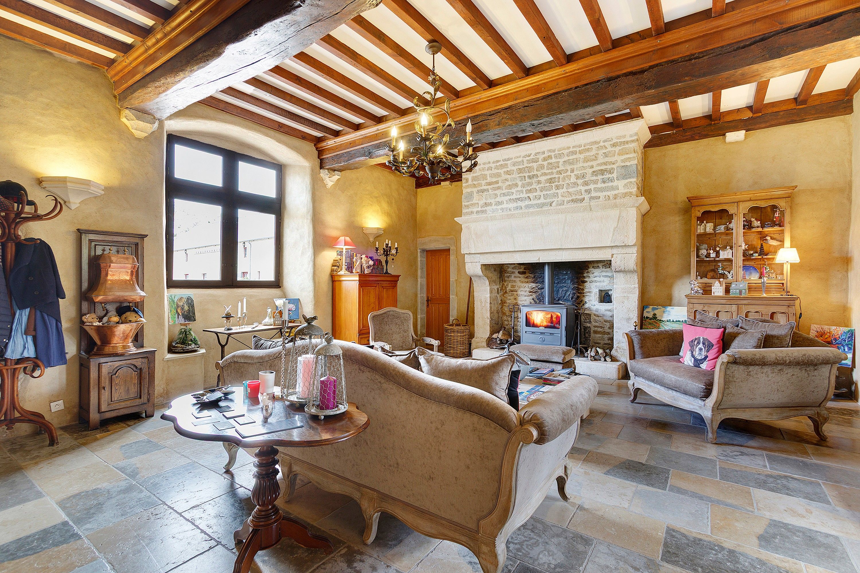 A traditional room with exposed wooden beams, a fireplace, and vintage furniture.