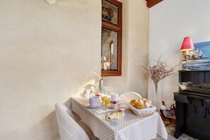Une table dressée pour le petit-déjeuner, avec un vase décoré de branches et une lampe.