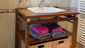 A bathroom with a wooden vanity, a mirror, a sink, and storage baskets.