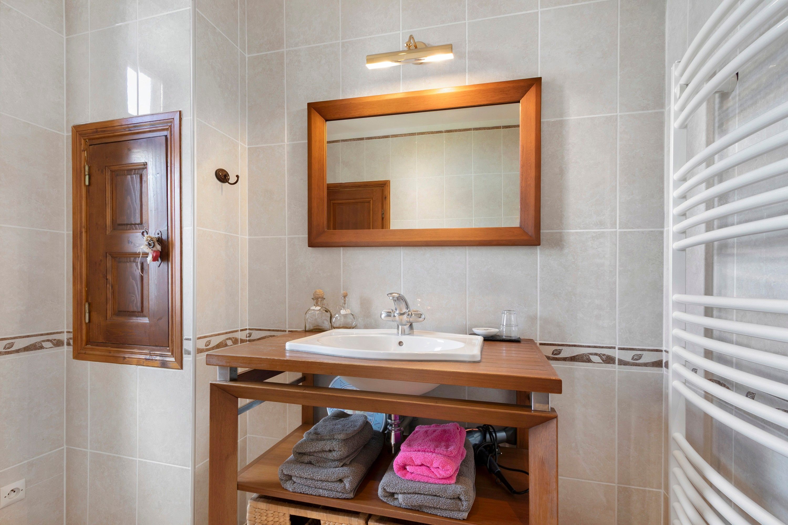 Une salle de bain avec un meuble-lavabo en bois, un évier, un miroir et un porte-serviettes.