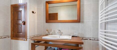 Une salle de bain avec un meuble-lavabo en bois, un évier, un miroir et un porte-serviettes.