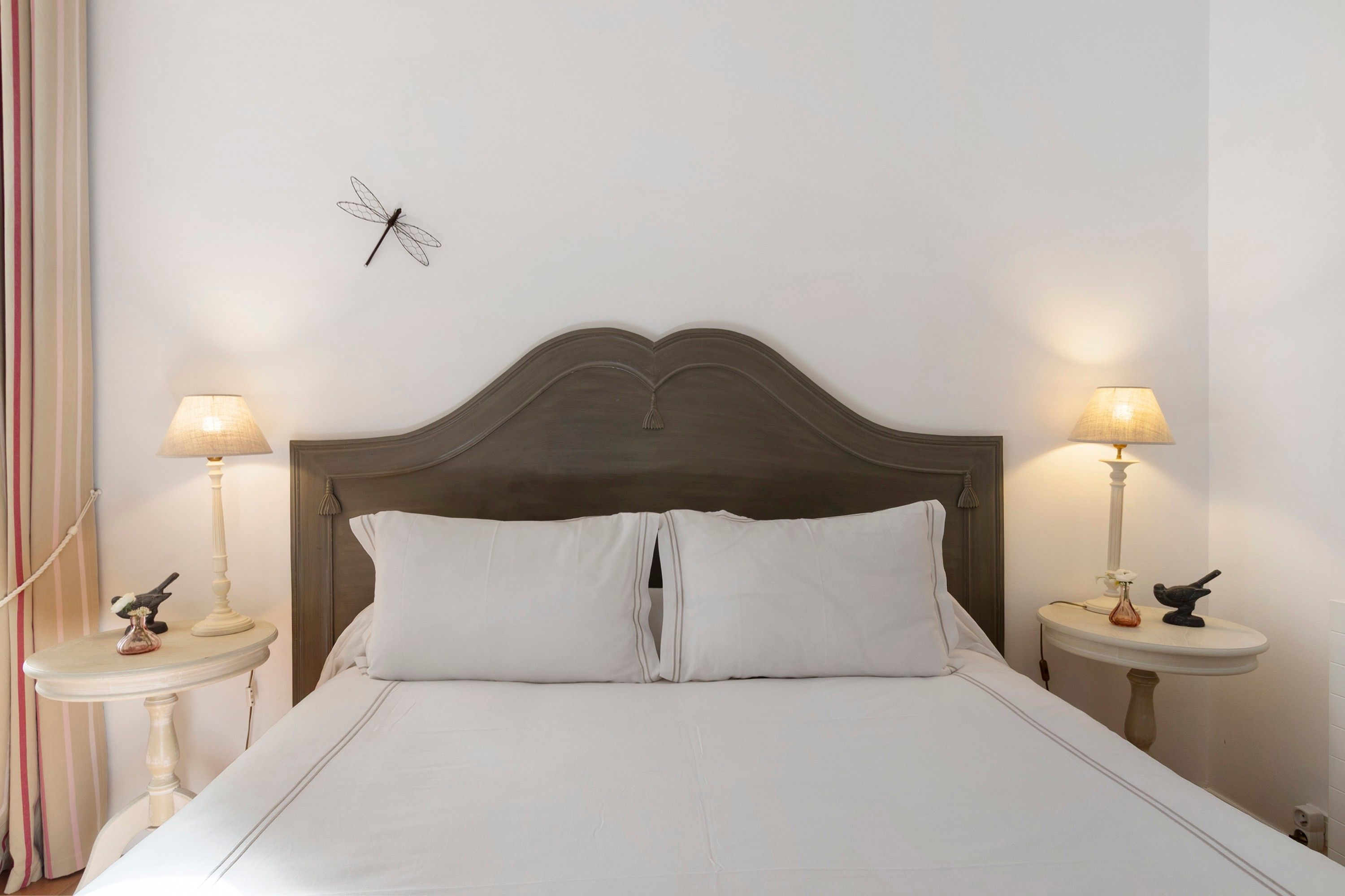 Un lit bien fait, avec une tête de lit en bois, deux tables de chevet avec des lampes et un élément décoratif fixé au mur.