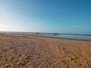 Ein Strand mit einem Steg, der sich ins Wasser erstreckt.