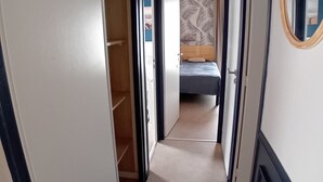 A hallway leading to a bedroom with a bed, a wardrobe, and a mirror on the wall. - Vacation home 250 m from the beach and forest. (Saint-Jean-de-Monts)
