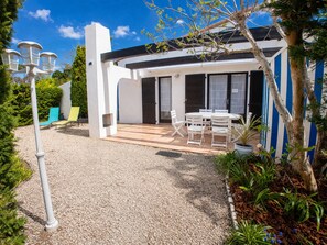 Una casa moderna con un patio, mobiliario exterior y un jardín.