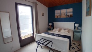 A bedroom with a bed, a window, a door, and a wall with a blue accent. - Vacation home 250 m from the beach and forest. (Saint-Jean-de-Monts)