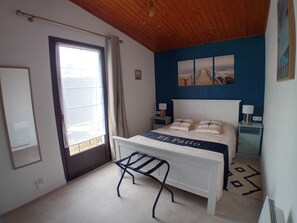 Ein Schlafzimmer mit Bett, Fenster, Tür und einer blauen Wand.