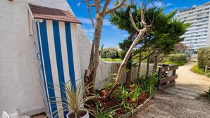 A building with a blue and white striped exterior, a small shed, and a gravel pathway leading to a wooden fence. - Vacation home 250 m from the beach and forest. (Saint-Jean-de-Monts)