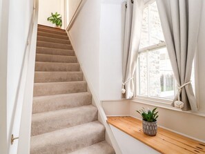 A carpeted staircase leading to a landing with a wooden bench and a potted plant. - Natland Hall Cottage in Kendal (Kendal)
