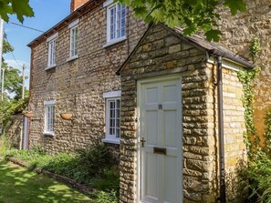 A stone building with a white door marked '18', windows, and hanging baskets. - Old Rectory Cottage, Washingborough (Lincoln)