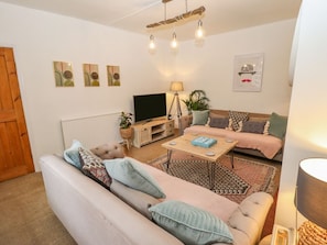 A living room with a sofa, a coffee table, a TV, and decorative items. - Old Rectory Cottage, Washingborough (Lincoln)