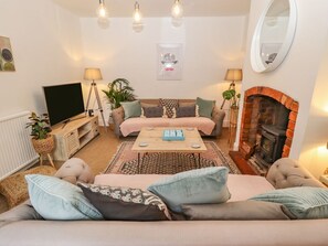 A cozy living room with a sofa, a coffee table, a fireplace, and a TV. - Old Rectory Cottage, Washingborough (Lincoln)