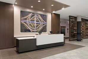 Uma receç ão com design moderno, uma grande pintura abstrata acima e um divisório de madeira ao fundo.