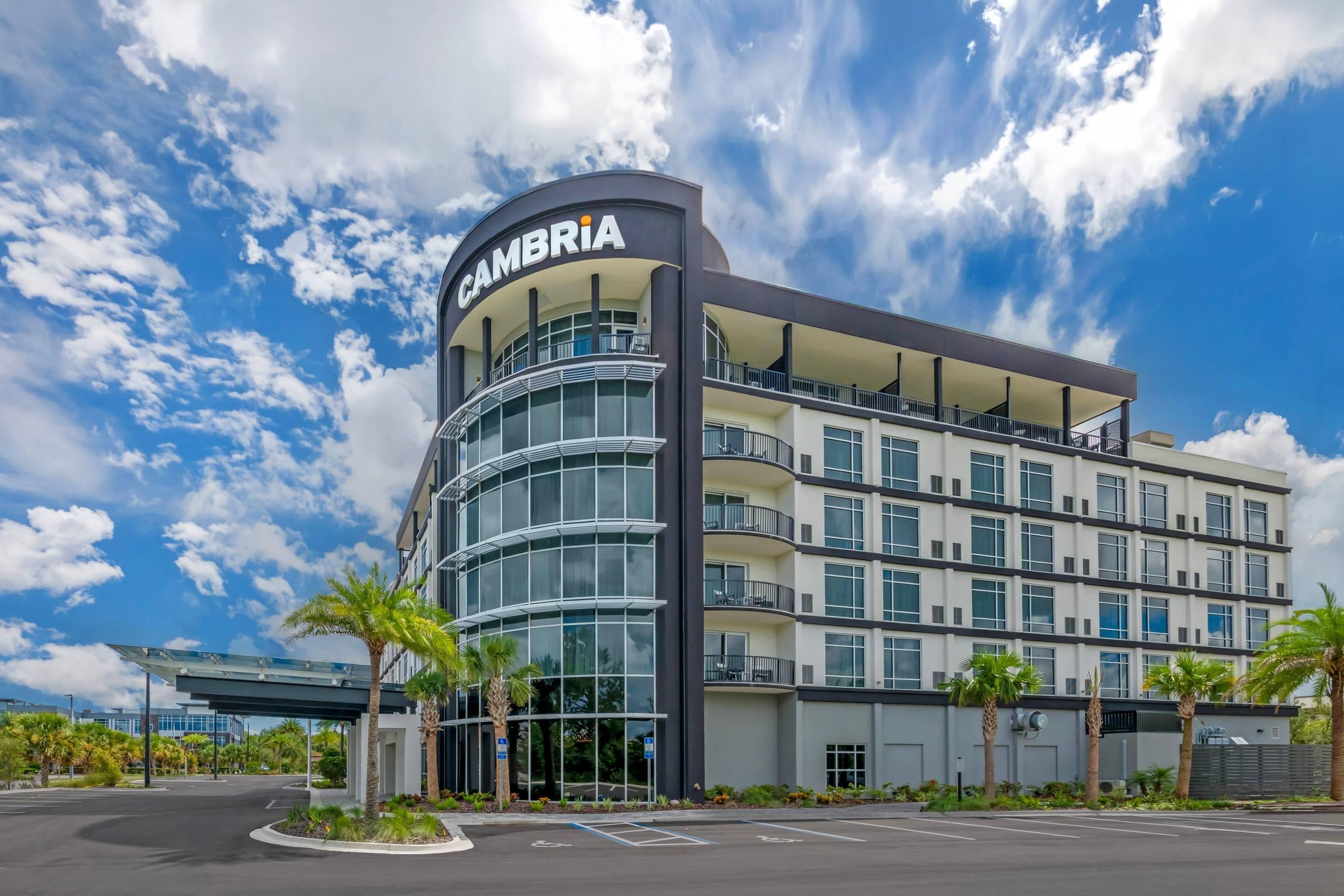 A multi-story hotel with a curved facade, balconies, and a clear sky.