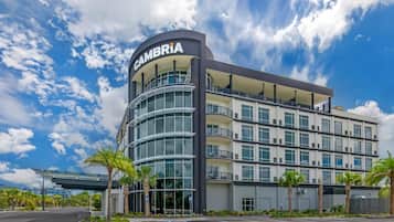 A multi-story hotel with a curved facade, balconies, and a clear sky.