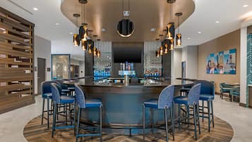 A modern bar area with a curved counter, bar stools, and pendant lighting.