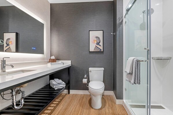 Ein modernes Badezimmer mit einem weißen Waschbecken, einer Toilette, einer Dusche und zwei gerahmten Kunstwerken an der Wand.