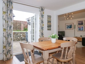 Un comedor con mesa y sillas de madera, una planta en maceta y vistas al exterior.
