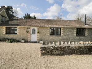 A stone building with a tiled roof, a white door, and a gravel driveway. - Orchard House Cottage, Malmesbury (Malmesbury)