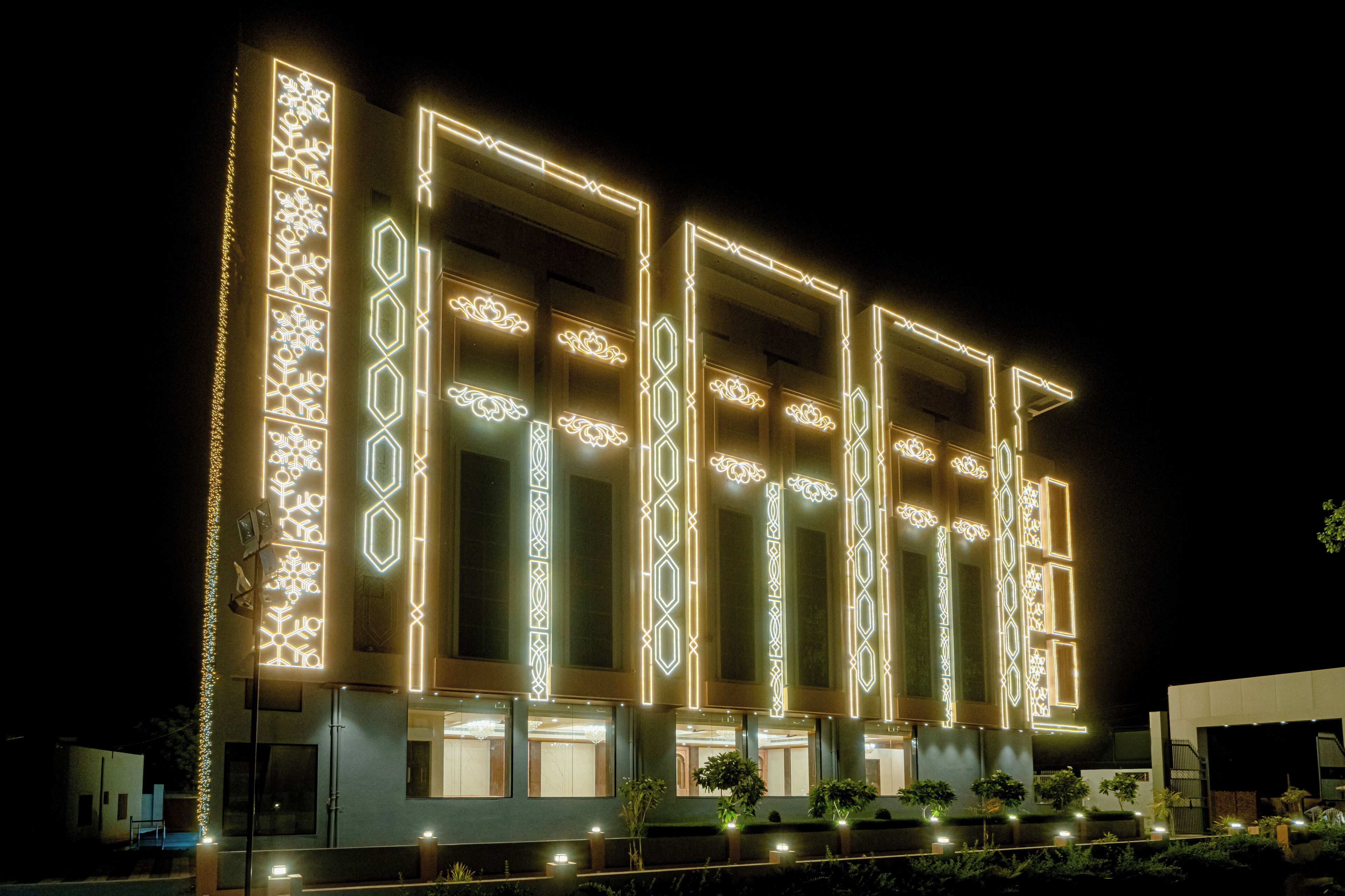 Un bâtiment moderne dont la façade est ornée de motifs géométriques illuminés, doté de grandes fenêtres et d’un toit plat.