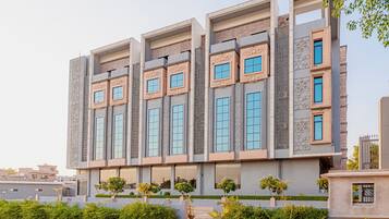 Un edificio de varios pisos con un diseño arquitectónico moderno, que cuenta con ventanas amplias y elementos decorativos.