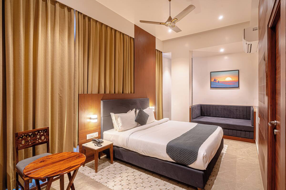 Une chambre d’hôtel équipée d’un lit, d’une table de chevet, d’une chaise et d’un téléviseur fixé au mur.