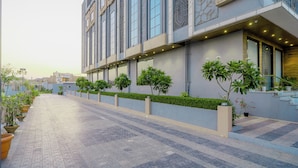 A modern building with a long, straight pathway lined with potted plants and a series of windows.
