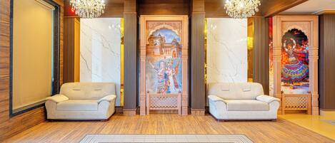A lobby with two sofas, a patterned rug, and a decorative wall with a mural.