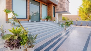 A modern building with a staircase leading to a balcony, surrounded by potted plants.