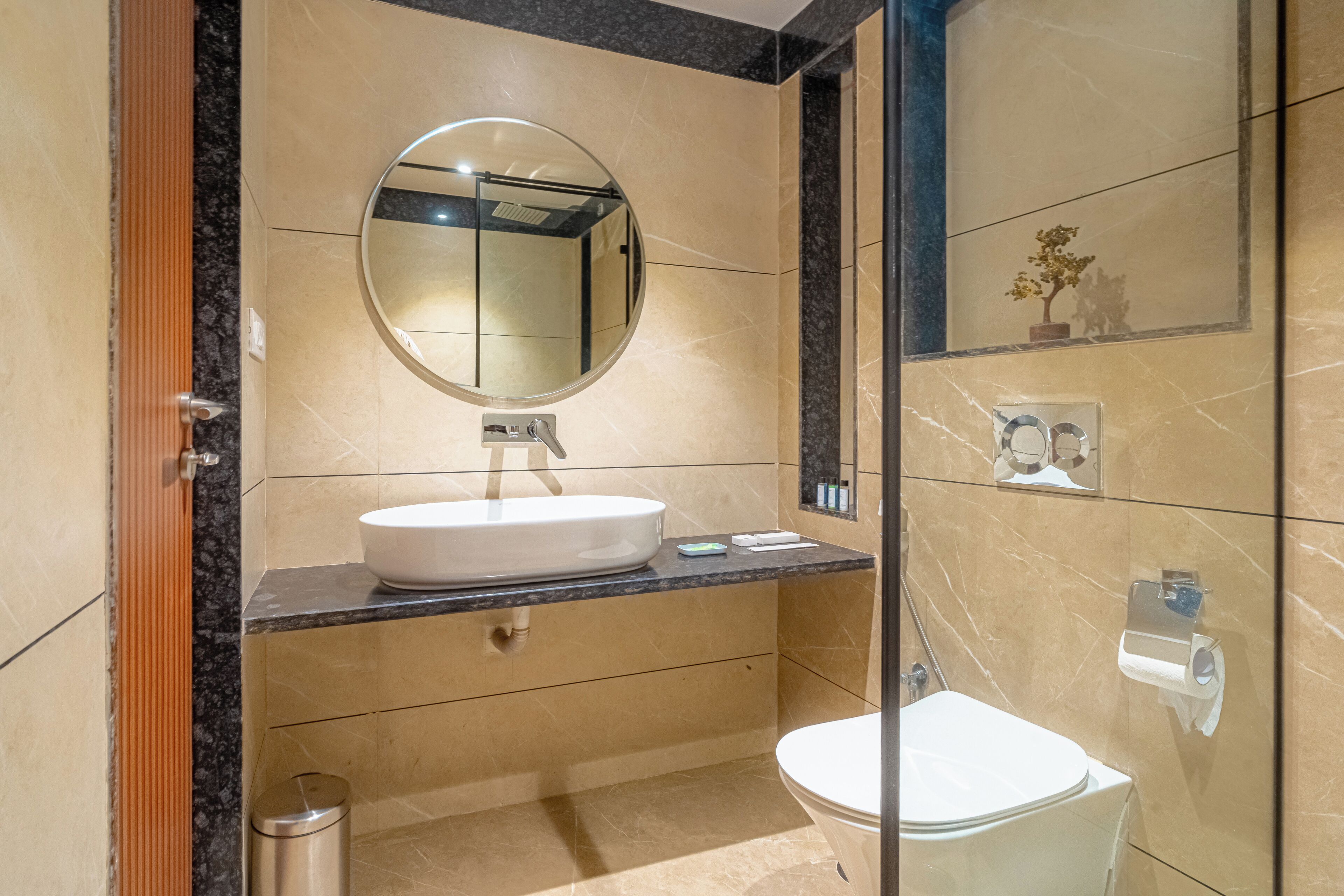 Un baño moderno con un espejo redondo, lavamanos blanco y retrete.