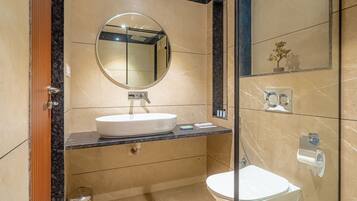 Un baño moderno con un espejo redondo, lavamanos blanco y retrete.
