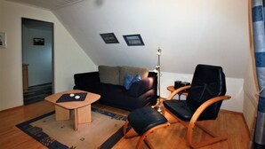 Ett vardagsrum med en soffa, två fåtöljer, ett soffbord och en lampa.