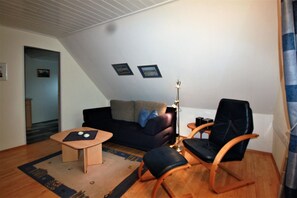 A living room with a sofa, two chairs, a coffee table, and a lamp. - Pidder Lyng - FW 4 - Holiday apartment Pidder Lyng FW 4 - close to the beach, with WLAN & (Utersum)
