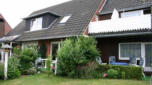 Ett tvåvåningshus med ett sluttande tak, en inhägnad trädgård och ett garage som syns.