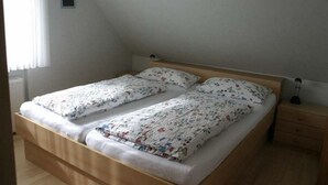 En säng för en person med blommigt sänglinne i ett rum med ett sluttande tak.