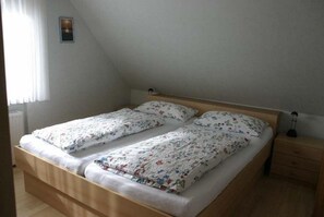 A twin bed with floral bedding in a room with a sloped ceiling. - Pidder Lyng - FW 4 - Holiday apartment Pidder Lyng FW 4 - close to the beach, with WLAN & (Utersum)