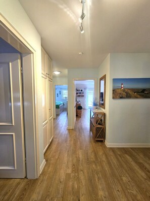A hallway with wooden flooring, white walls, and a painting of a lighthouse. - Herrenhof - Holiday apartment 8 on the ground floor - Holiday apartment on the ground floor in Wrixum on Föhr: 76 (Wrixum auf Föhr)