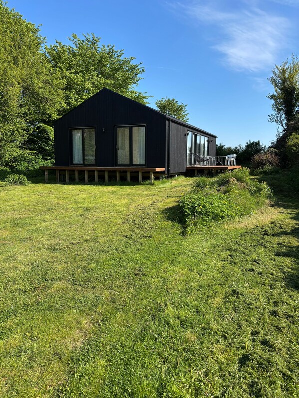 A modern black building with large windows and a deck area. - Stylish Cottage Near Beach, Cliff and Harbour Life (Rodvig Stevns)
